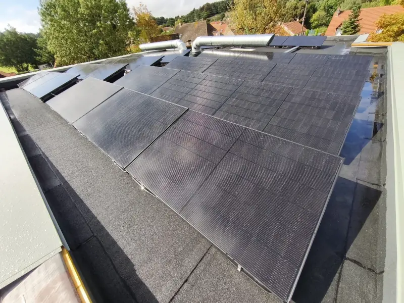Panneaux photovoltaïques encore mouillés après la pluie sur une toiture-terrasse équipée par JCBO Toit ENR